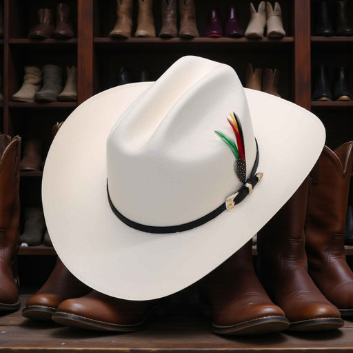 White cowboy hat with decorative band on a wooden surface with boots in the background