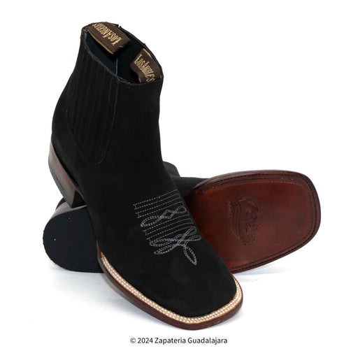 Black cowboy boot with brown sole and decorative stitching on a white background