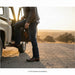 Person getting into a vehicle on a road with a scenic background