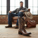 Man sitting on a leather chair with cowboy boots in the foreground