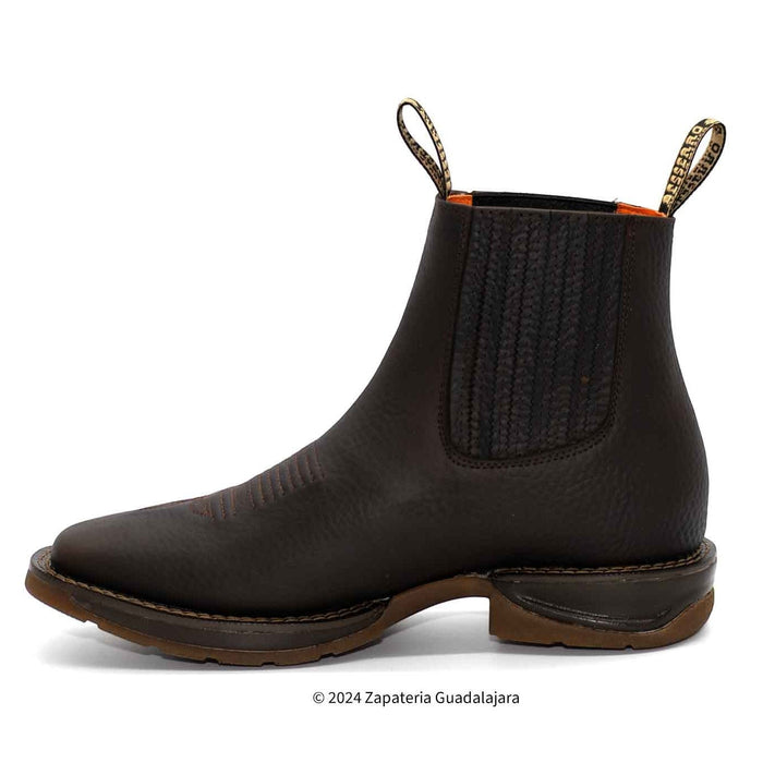 Black Chelsea boot with brown sole on a white background