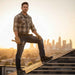 Man standing on a rooftop with a city skyline in the background