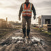 Person wearing a high-visibility vest and boots on a construction site