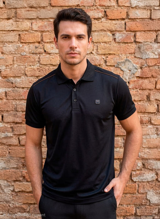Man wearing a black polo shirt against a brick wall