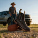 a pair of brown caiman belly leather boots with a cowboy standing in the background