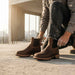 Person wearing brown Chelsea boots outdoors with a blurred background
