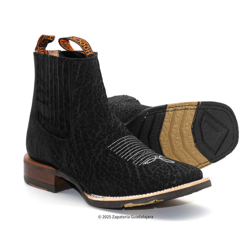 Pair of black textured boots with brown soles on a white background