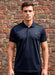 Man wearing a navy polo shirt against a brick wall