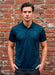 Man wearing a teal polo shirt against a brick wall