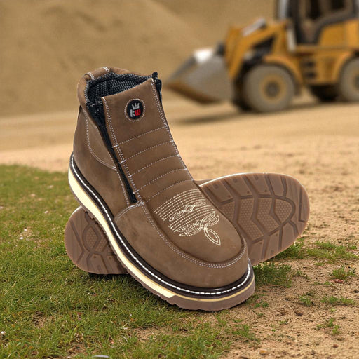 Brown work boots on grass with a blurred construction vehicle in the background