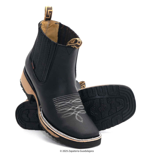 Black leather boots with tan soles and decorative patterns on a white background
