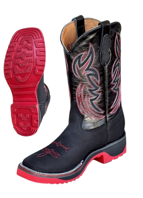 A pair of western boots shown on a plain white background, with one boot standing upright to display the side and the other lying down to show the red outsole. The boots are black with pink and white embroidered patterns on the shaft and a red outsole.