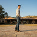 Man standing on a stone path in front of a large house with mountains in the background