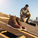 Brown work boots on a roof with a person working in the background