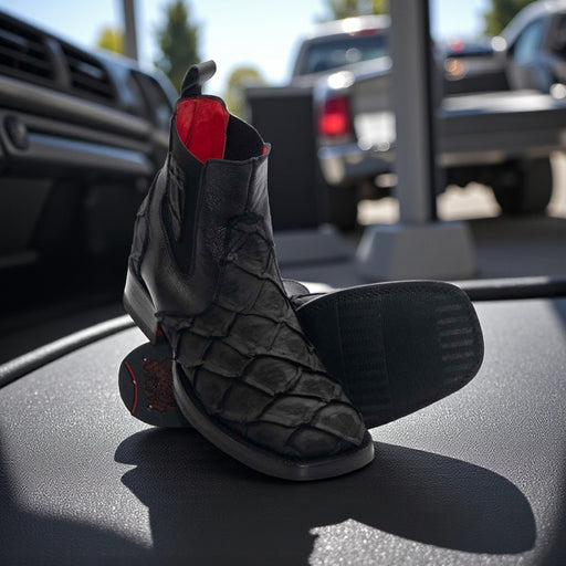 Black textured boots with red soles on a car dashboard, with a blurred outdoor background.