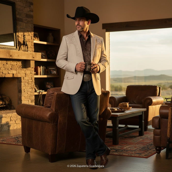 Man in a stylish outfit with a cowboy hat in a living room with a fireplace and large window.