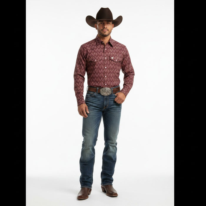 A man modeling a long-sleeve western shirt with a burgundy and brown geometric pattern, paired with blue jeans, a brown cowboy hat, and brown boots against a white studio background.