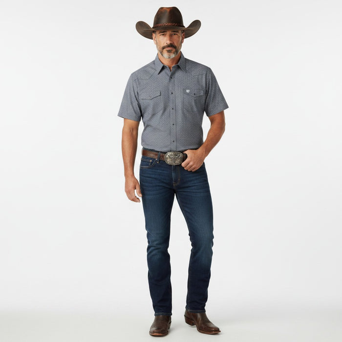 A man modeling a short-sleeve western button-down shirt in heathered blue-gray, paired with dark blue jeans, a brown cowboy hat, and brown leather boots against a plain white studio background.