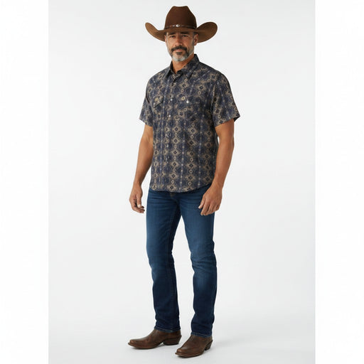 A man modeling a short-sleeve button-down shirt with a dark navy and brown geometric pattern, paired with blue jeans, brown cowboy boots, and a brown cowboy hat against a white studio background.