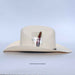 Beige cowboy hat with a feather on a light blue background