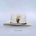 White cowboy hat with a feather on a light gray background