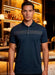Man wearing a dark blue polo shirt with a patterned chest design in a bar setting.
