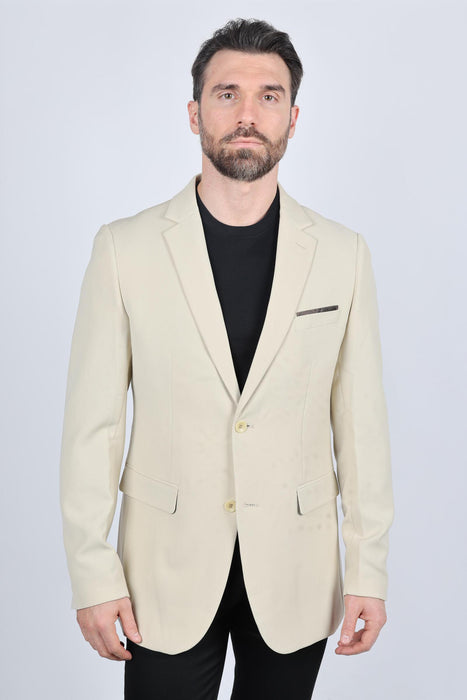 Man wearing a beige blazer over a black shirt on a white background