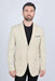 Man wearing a beige blazer over a black shirt on a white background