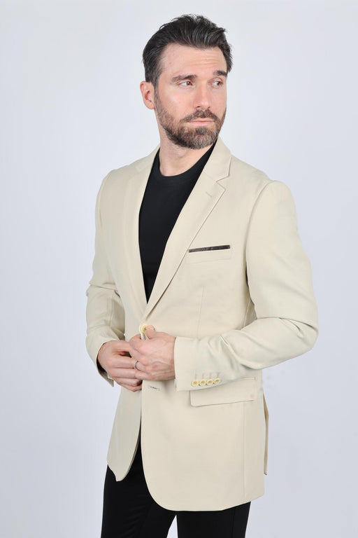 Man wearing a beige blazer over a black shirt on a white background