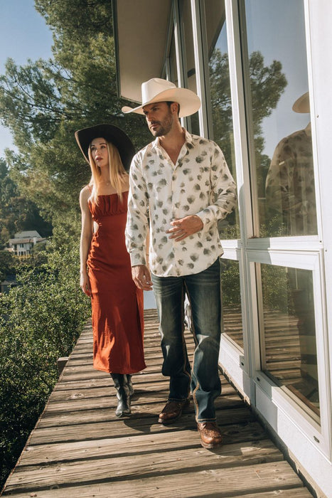 Man and woman walking on a wooden deck with trees in the background
