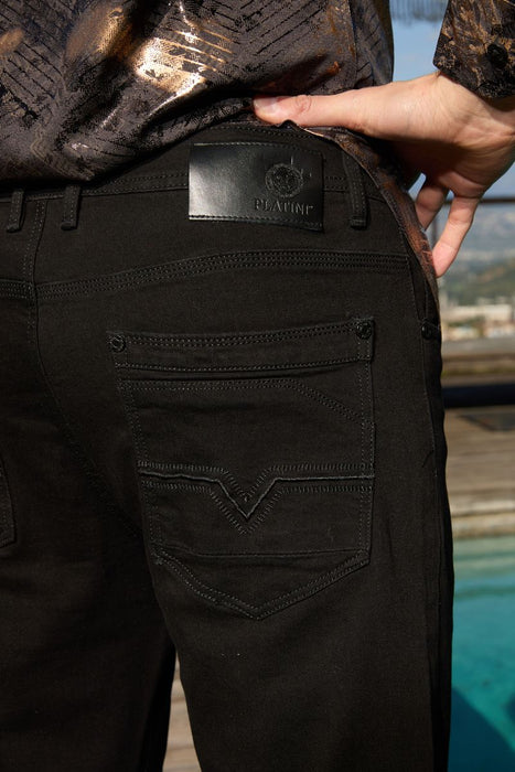 Close-up of black pants with a brand label, blurred background