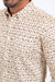 Beige shirt with a subtle pattern worn by a person on a white background