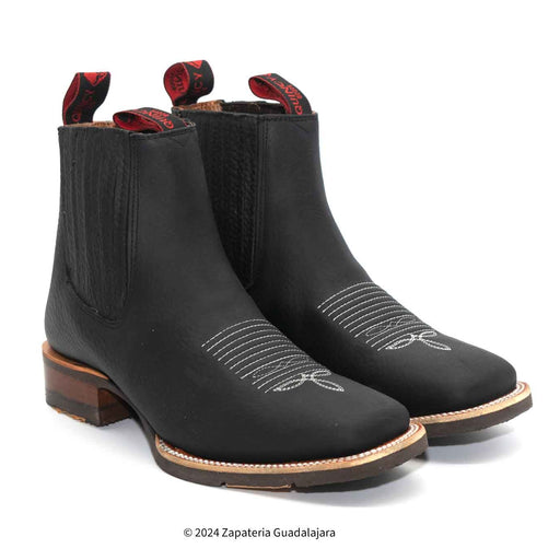 Pair of black Chelsea boots with red accents on a white background