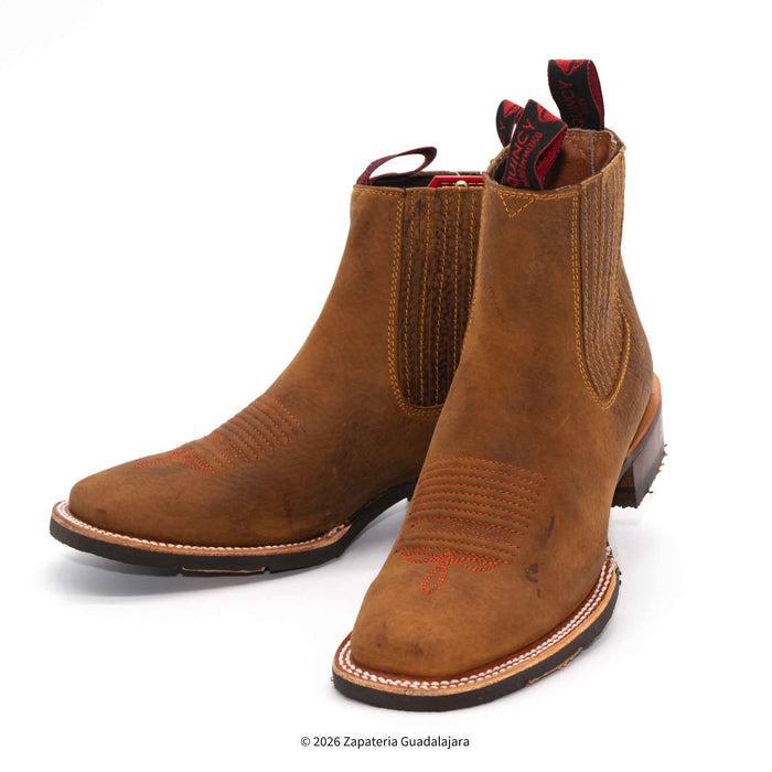 a pair of tan brown leather boots with rubber sole and white background