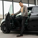 Man getting into a black car wearing black boots with red sole