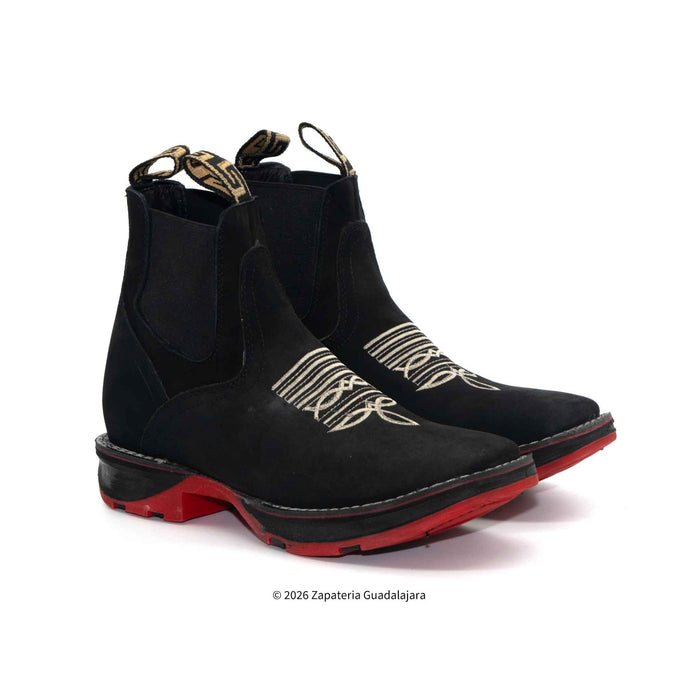Black Chelsea boots with red soles on a white background