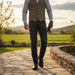 Man in formal attire walking on a stone path with a scenic background