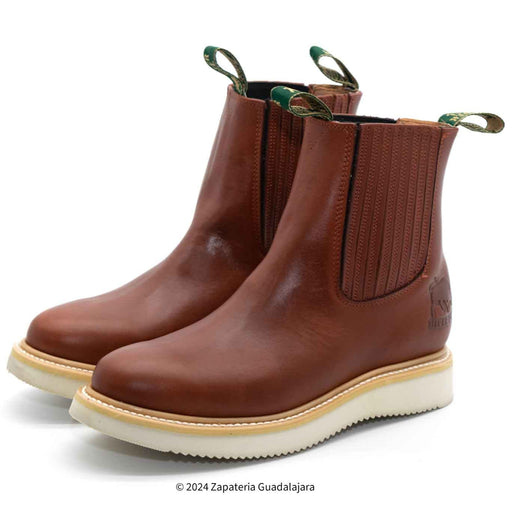 A brown leather work boot with a pull-on design and non-slip sole, alongside a white and beige sole detail.