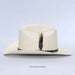 An off-white cowboy hat with a black band and a decorative feather accent on the front, photographed against a light gray background.