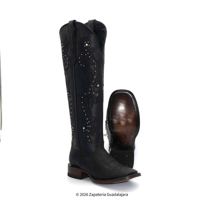 Black cowboy boots with studded details on a white background
