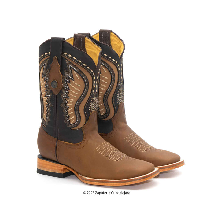 A pair of brown leather cowboy boots with black shaft panels and tan western embroidery, shown on a white background.